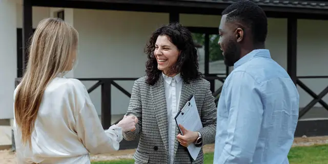 Real estate agent greeting new property owners outside their home